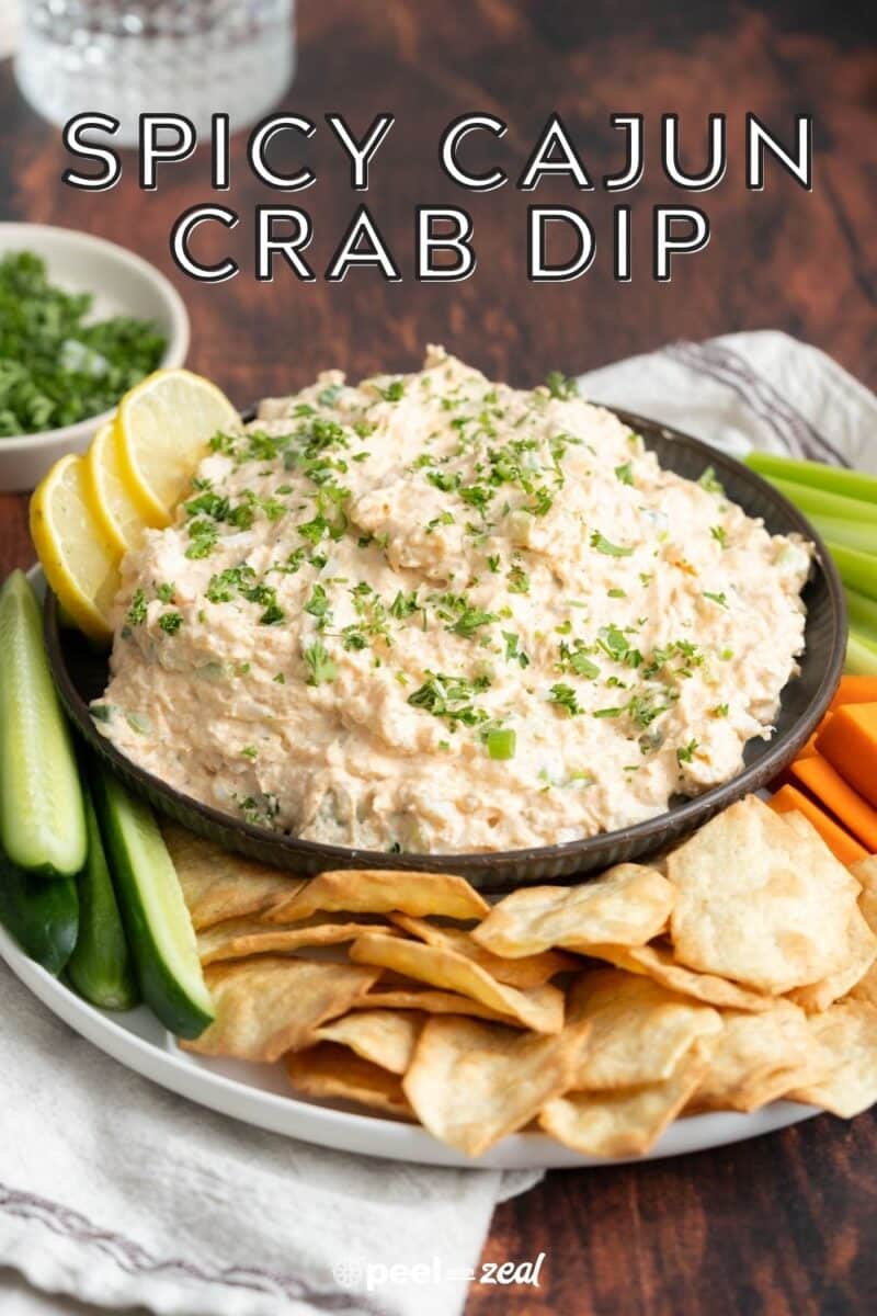 Cold Cajun crab dip in a bowl with sides of vegetables and crackers.
