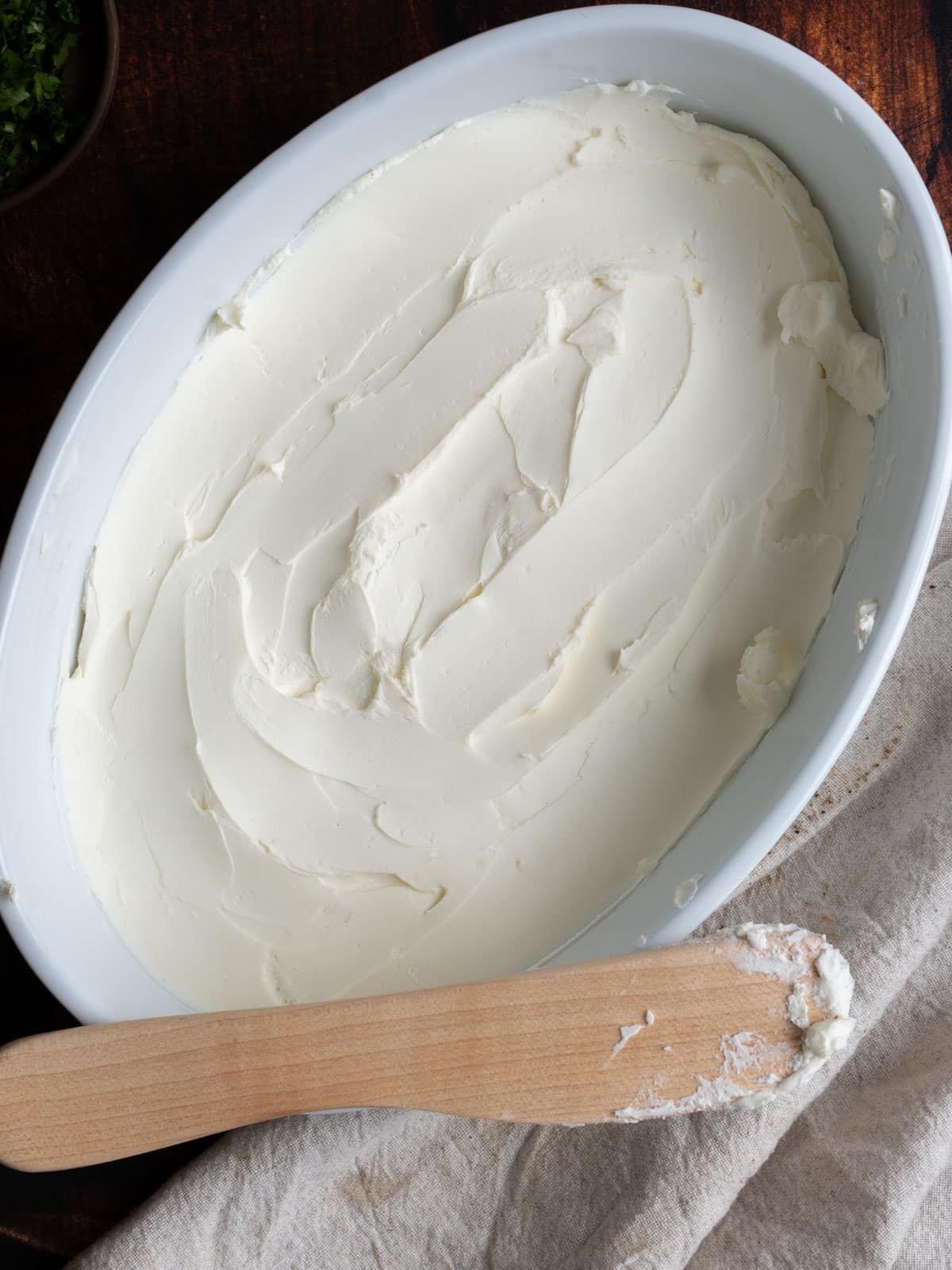 Cream cheese spread evenly at the bottom of a dish.