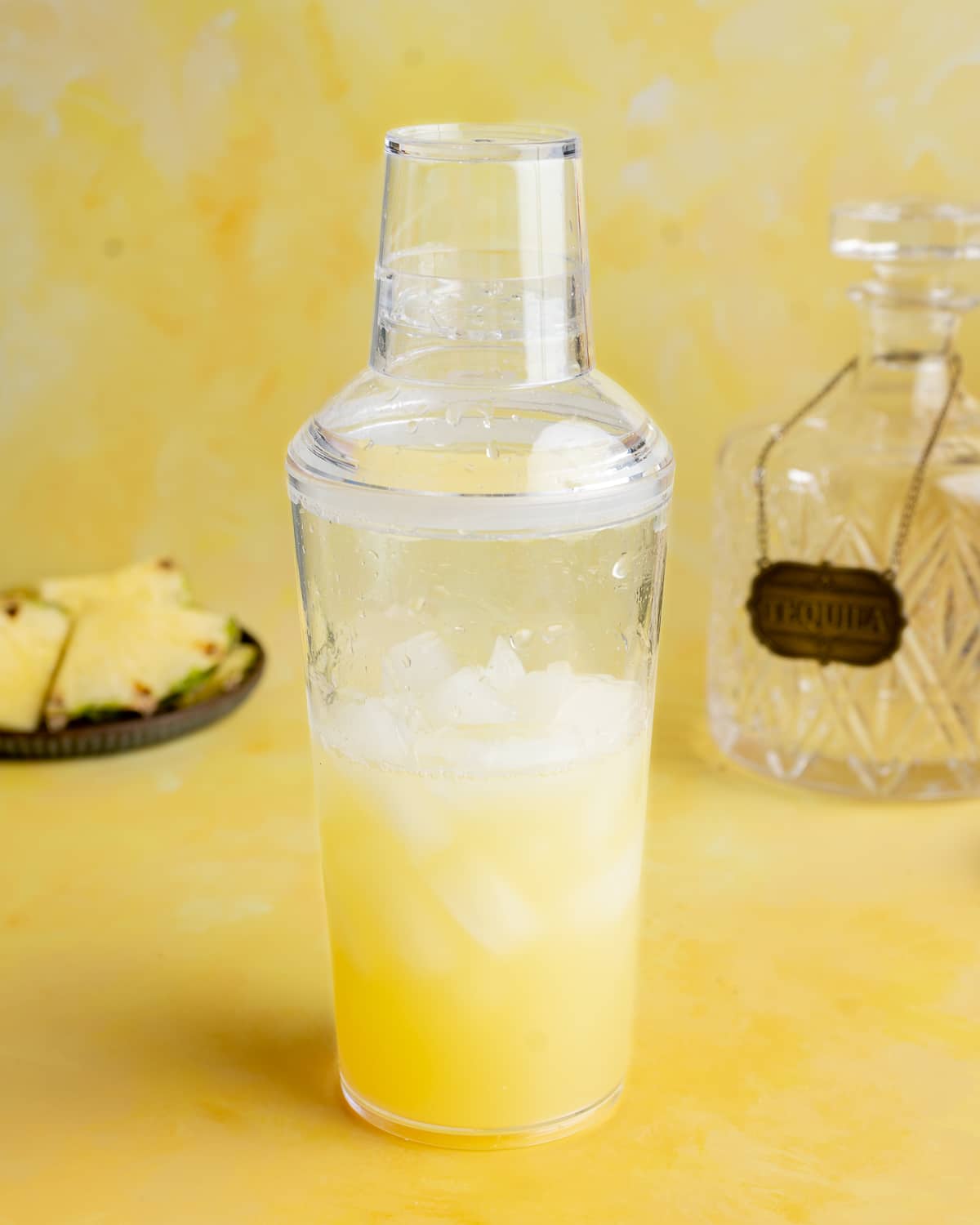 Pineapple margarita ingredients in a cocktail shaker.