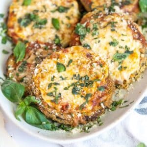 Eggplant parm topped with cheese and fresh basil on a plate.