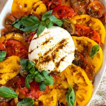 Burrata caprese salad on a serving platter with crostini.