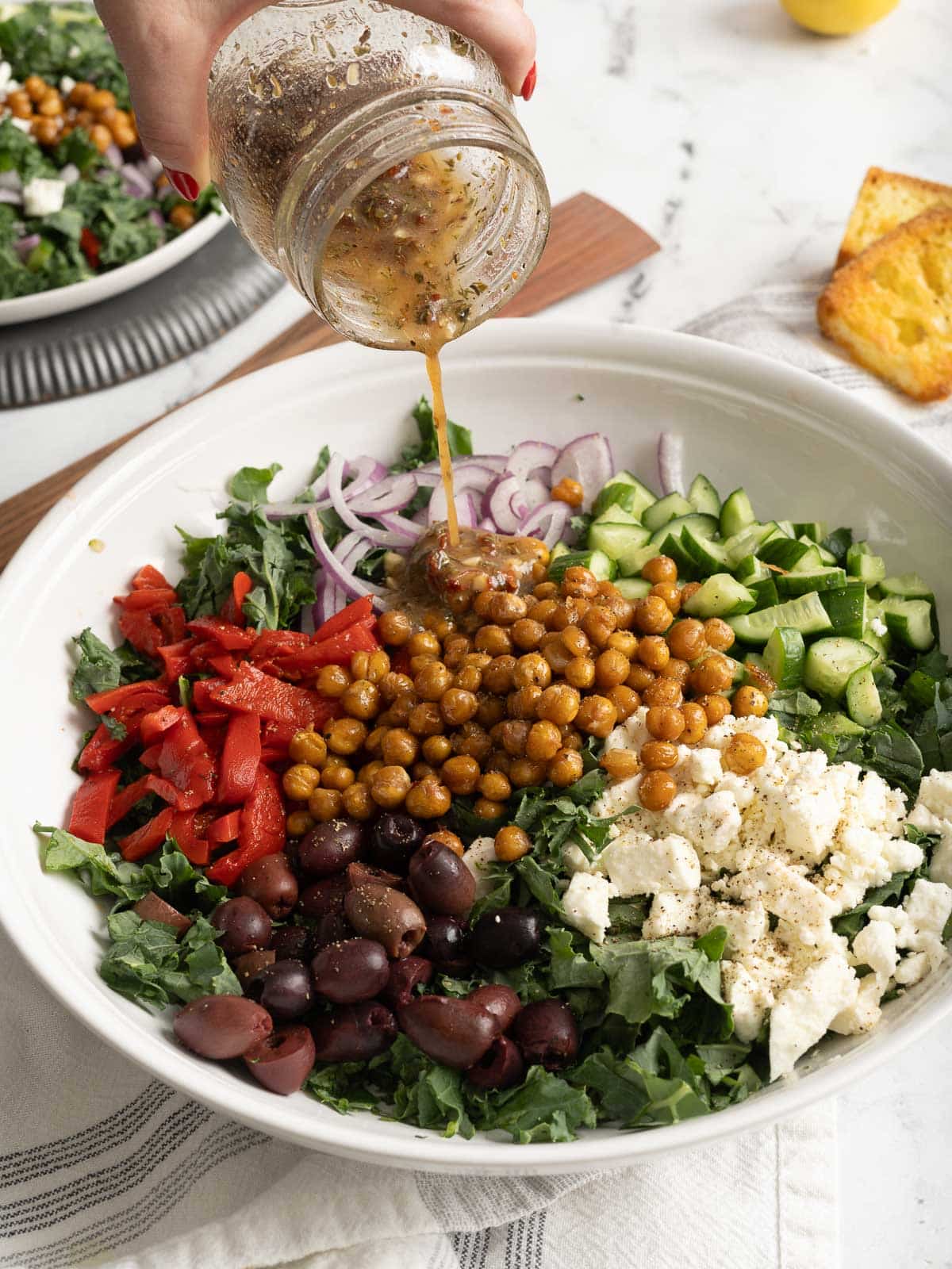 Pouring dressing on a kale salad in a bowl.