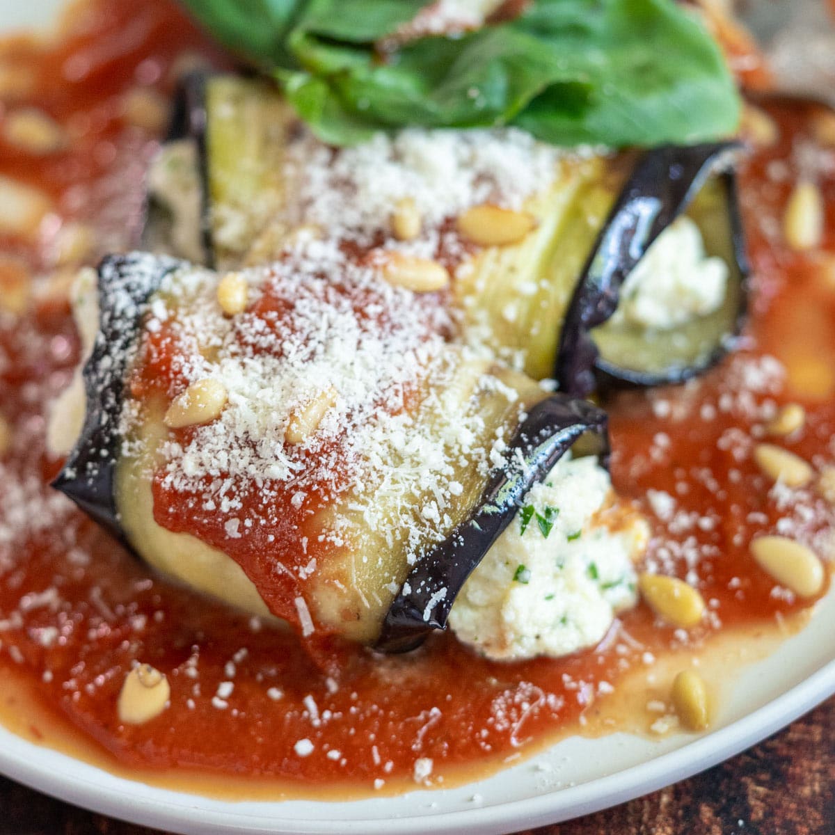 Eggplant ricotta rolls on a bed of tomato sauce.