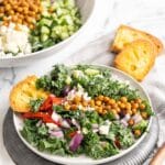 Greek kale salad being served with toasted bread.