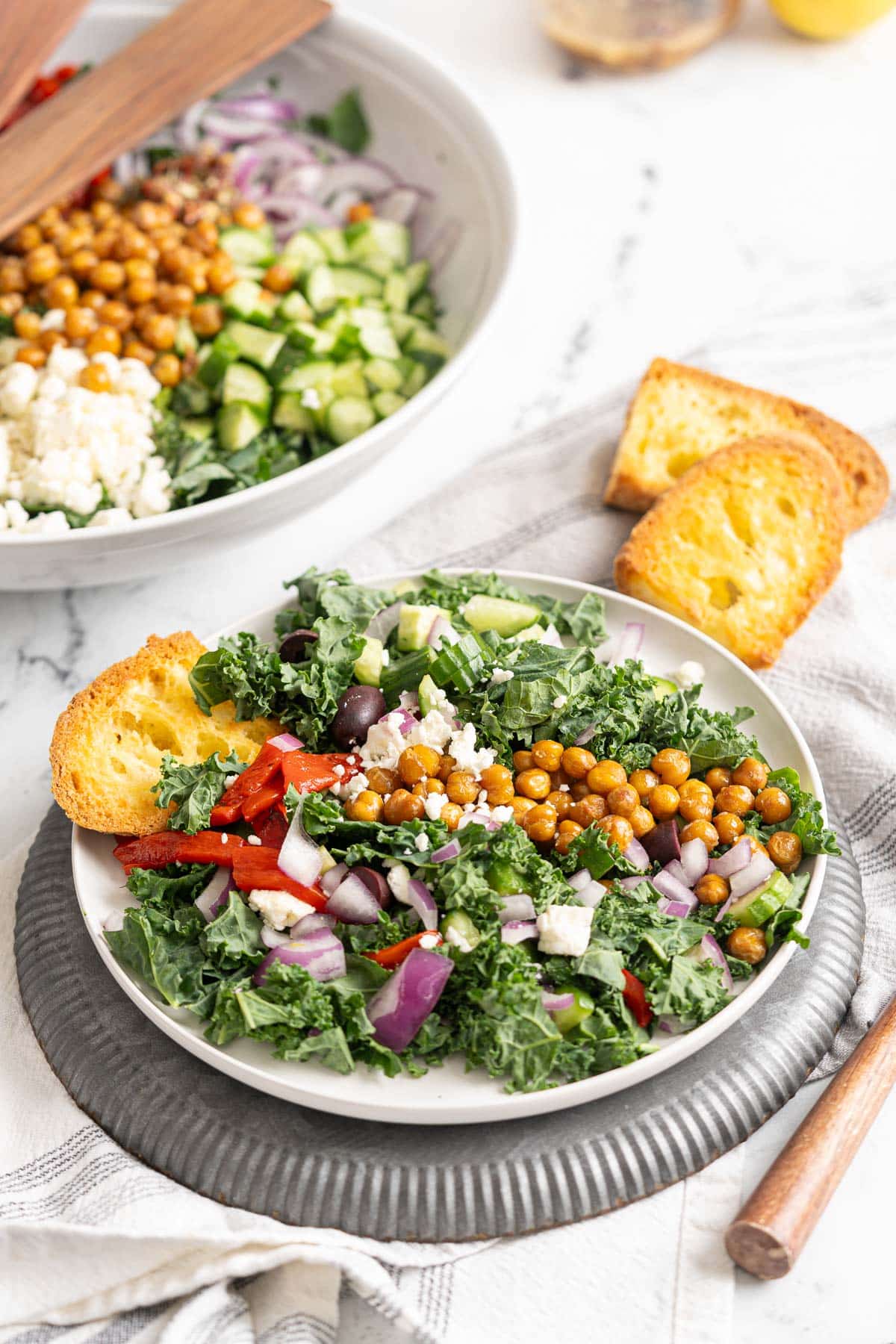 Greek kale salad being served with toasted bread. 