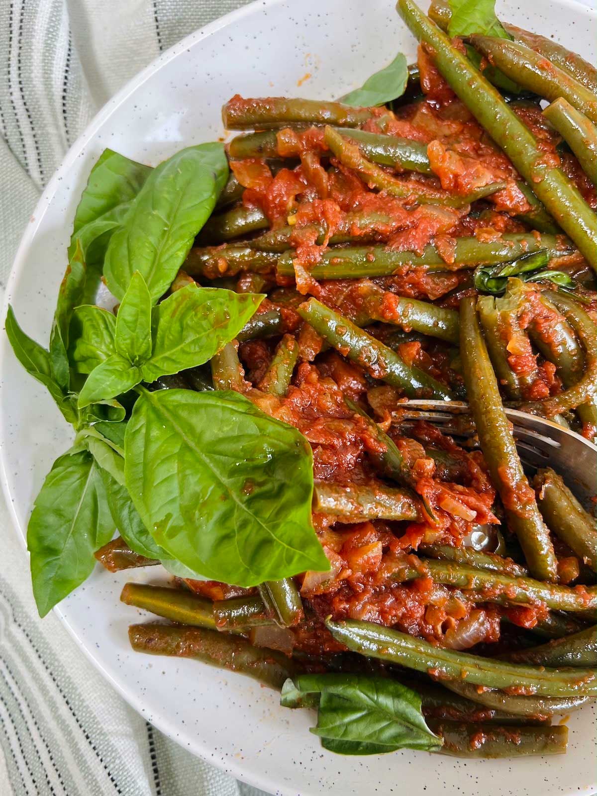 Green beans in tomato sauce topped with basil.