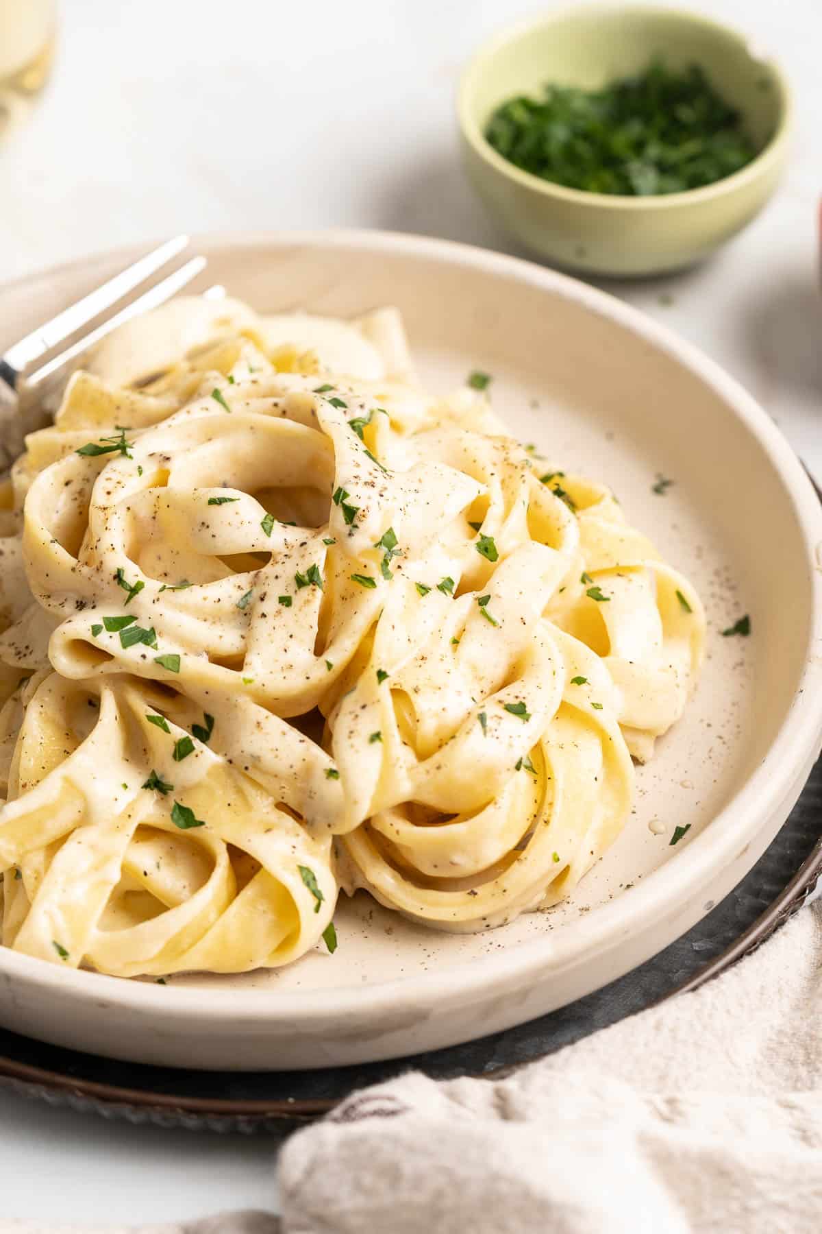 Homemade pasta with alfredo sauce on a plate with a fork.