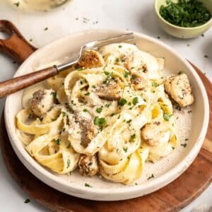 Chicken Alfredo pasta on a plate with a fork.