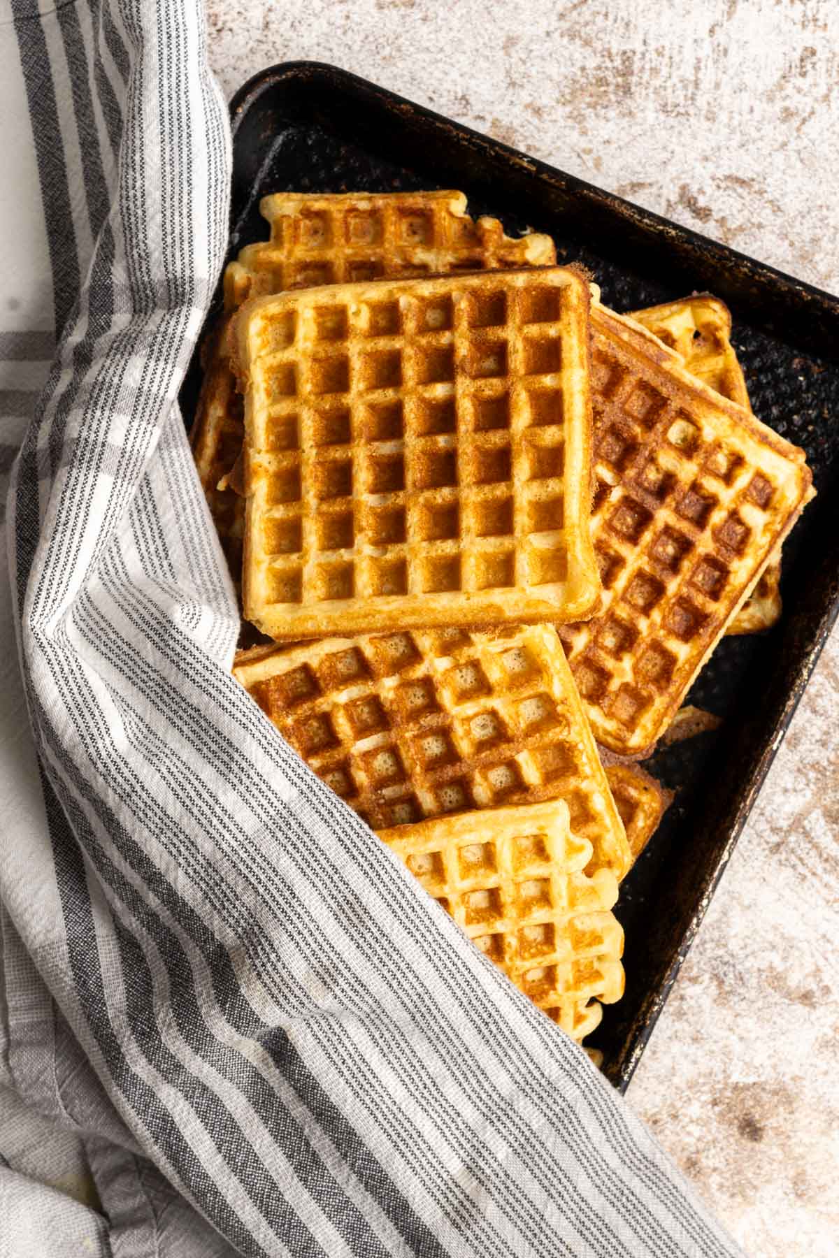 Gluten-free waffles are laid out in a black tray.