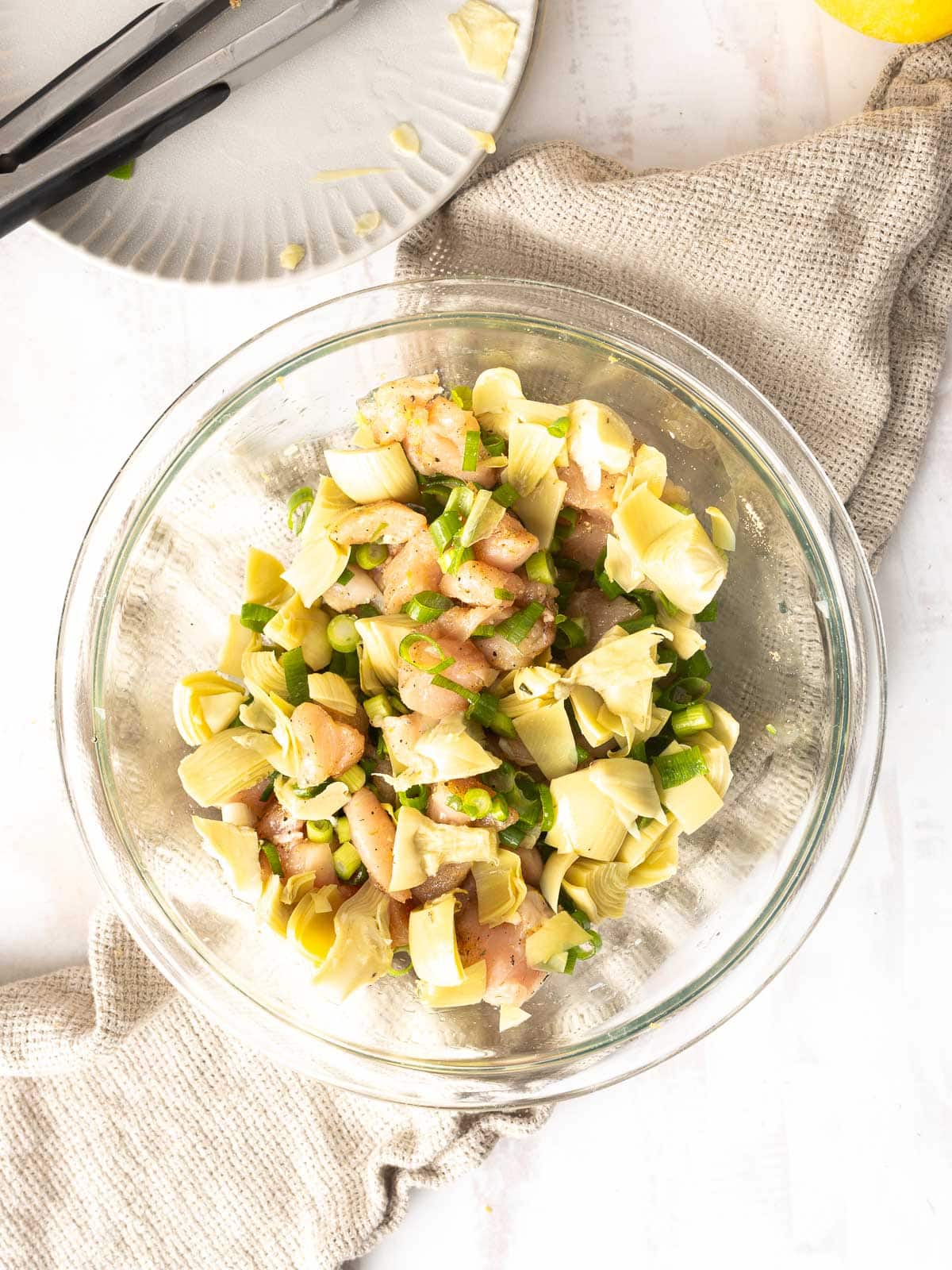 A bowl of mixed ingredients for Artichoke Chicken.⁣