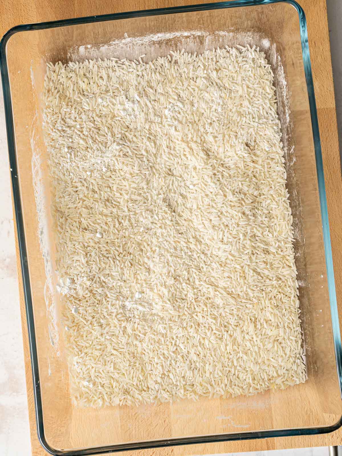 ⁣Rice grains layered in a baking dish.⁣ ⁣