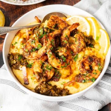 Cajun Shrimp and Grits served in a dish with lemon slices.