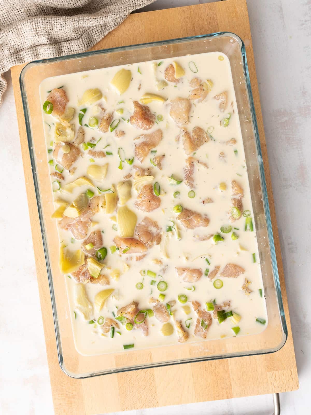 Artichoke Chicken mixture in a baking dish, ready to be baked.⁣