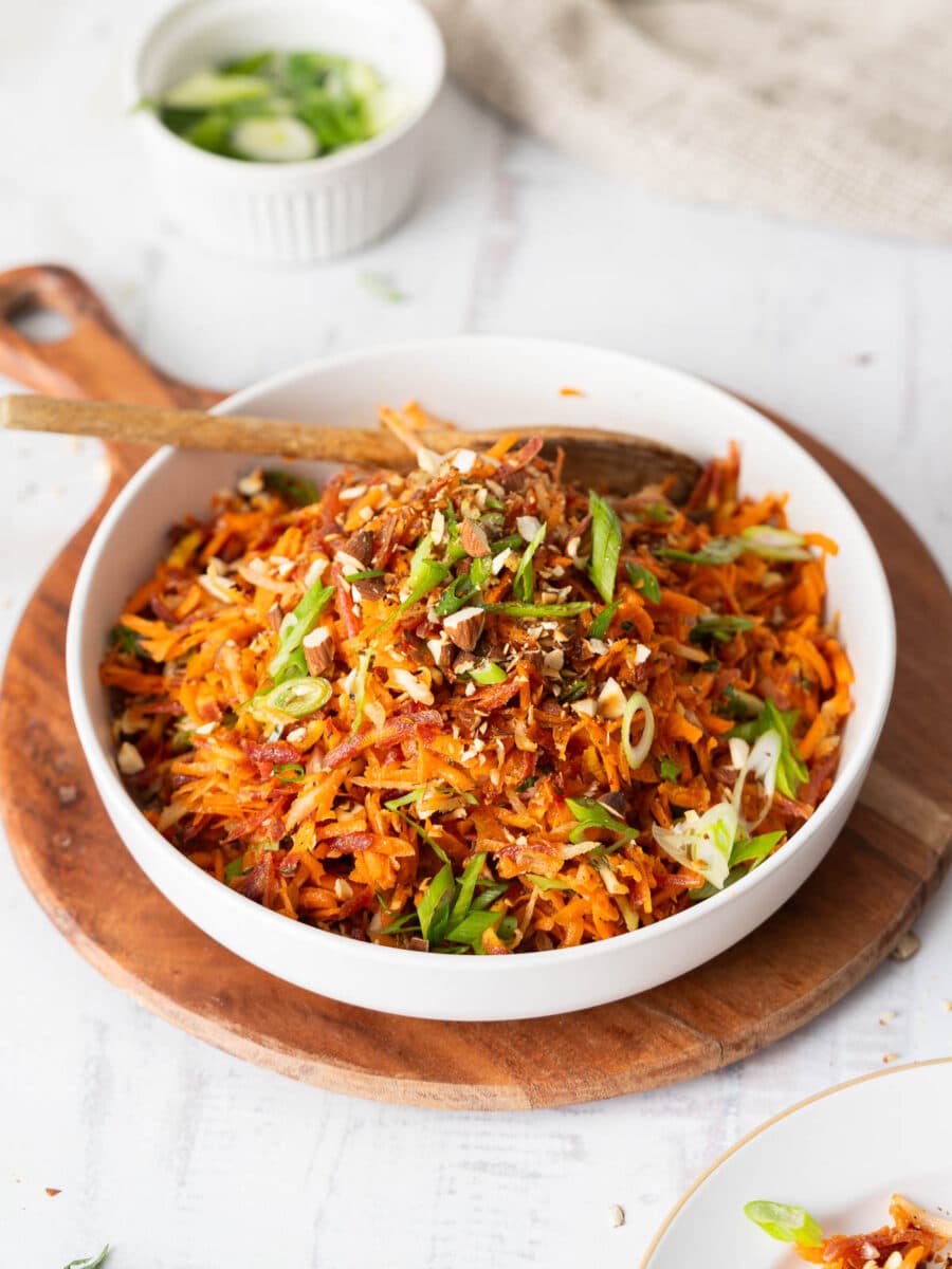 French carrot salad served in a bowl on a wooden tray.