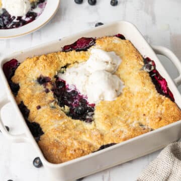 Blueberry cobbler served in a baking dish with vanilla ice cream.⁣ ⁣