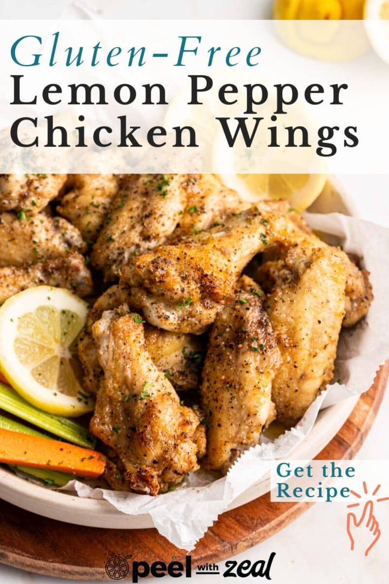 Lemon pepper chicken wings, adorned with minced parsley, lemon slices, carrot batons, and fresh parsley sprigs, on a rustic wooden platter.⁣