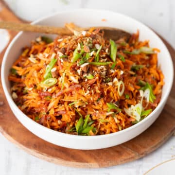 French carrot salad served in a bowl on a wooden tray.