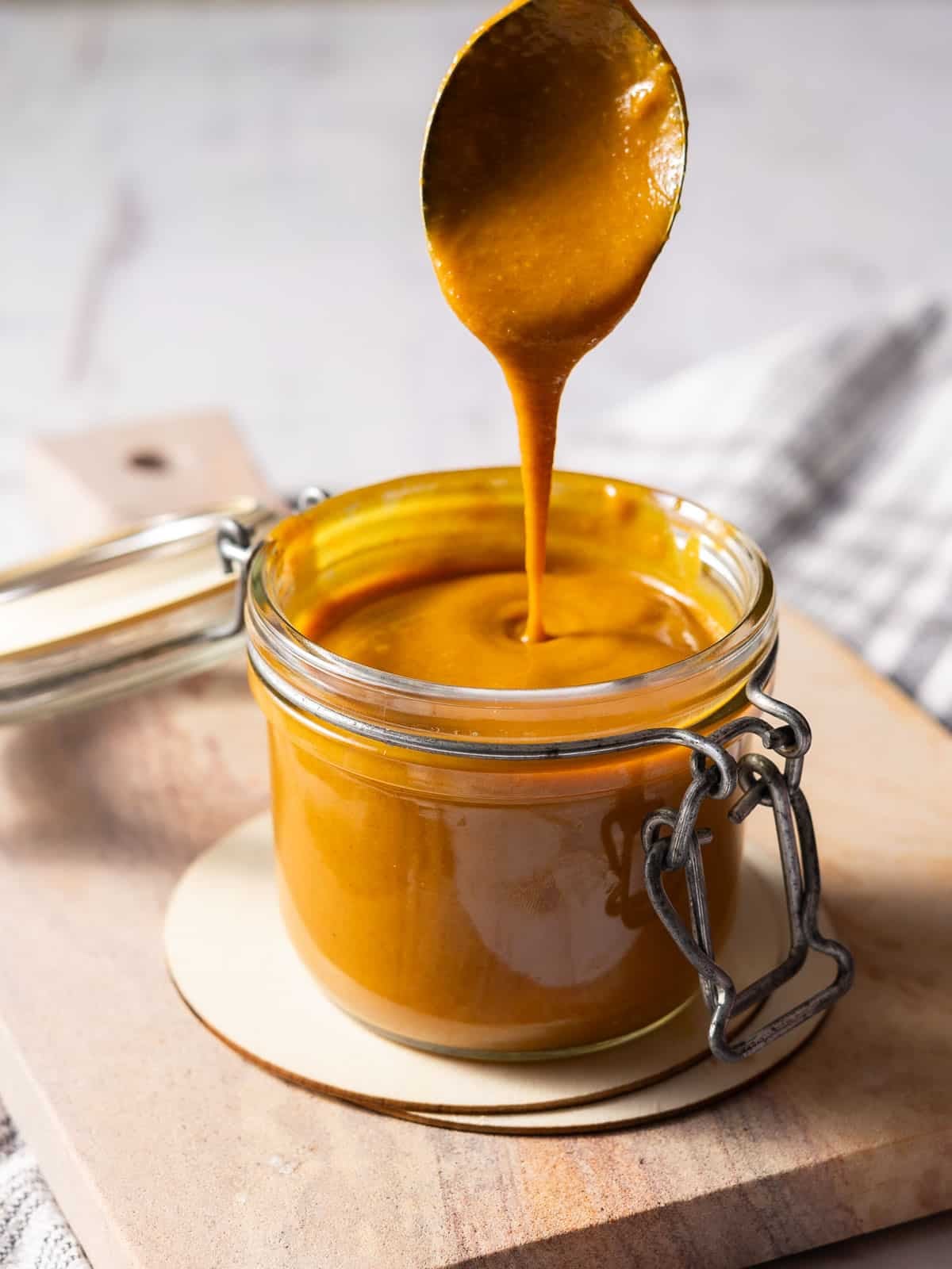 Caroline barbeque sauce in the jar place on top of the wooden cutting board.