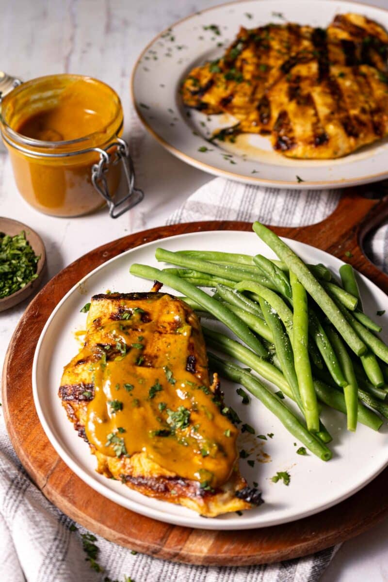 Caroline Barbeque serve a portion on a plate with sauteed green beans on top of a cutting board atop the table.