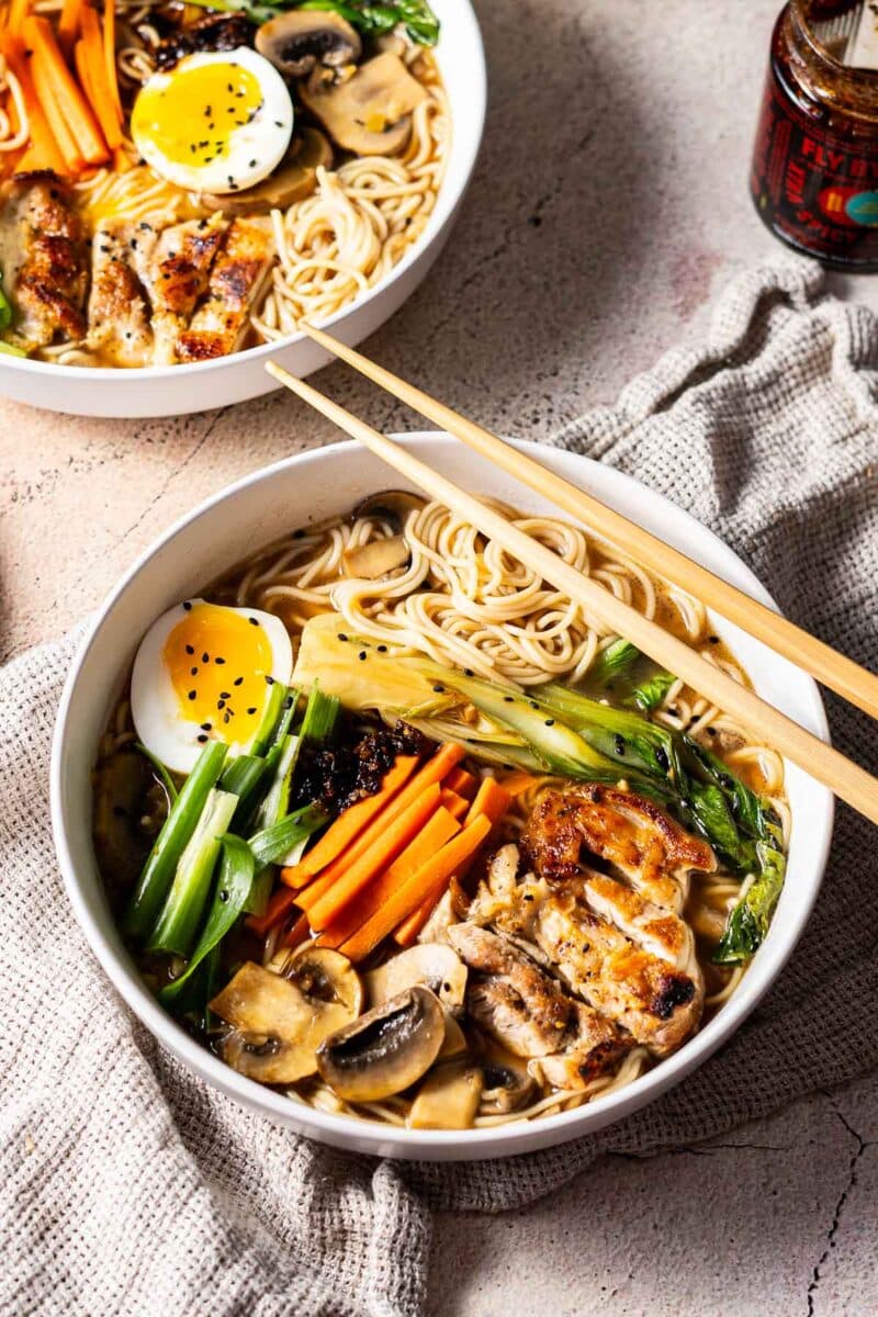 Bowl of ramen and the cooked vegetable garnish on the ramen serve on the table.