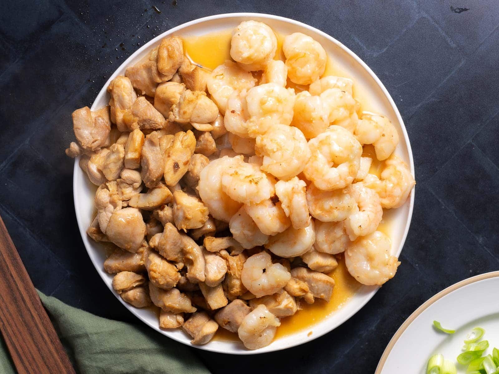 Chicken slices in cubes along with shrimp place in a white plate.