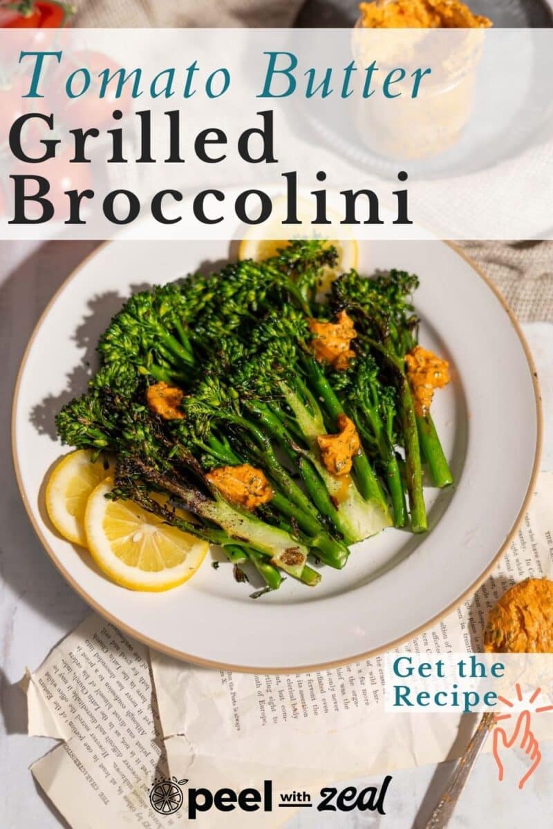 Plated roasted broccolini drizzled with tomato garlic butter garnished with lemon slices served on the table.