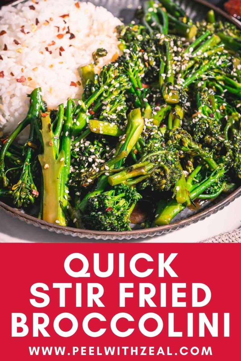 Stir fried broccolini in a platter with rice garnish with sesame seeds ans some chili flakes.