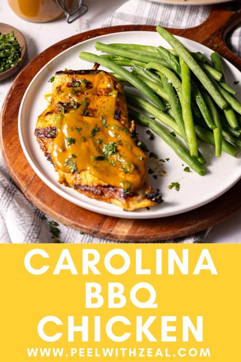 A plate of Carolina Chicken BBQ, garnished with spicy mustard sauce, is serve on a plate over the wooden board atop the table.