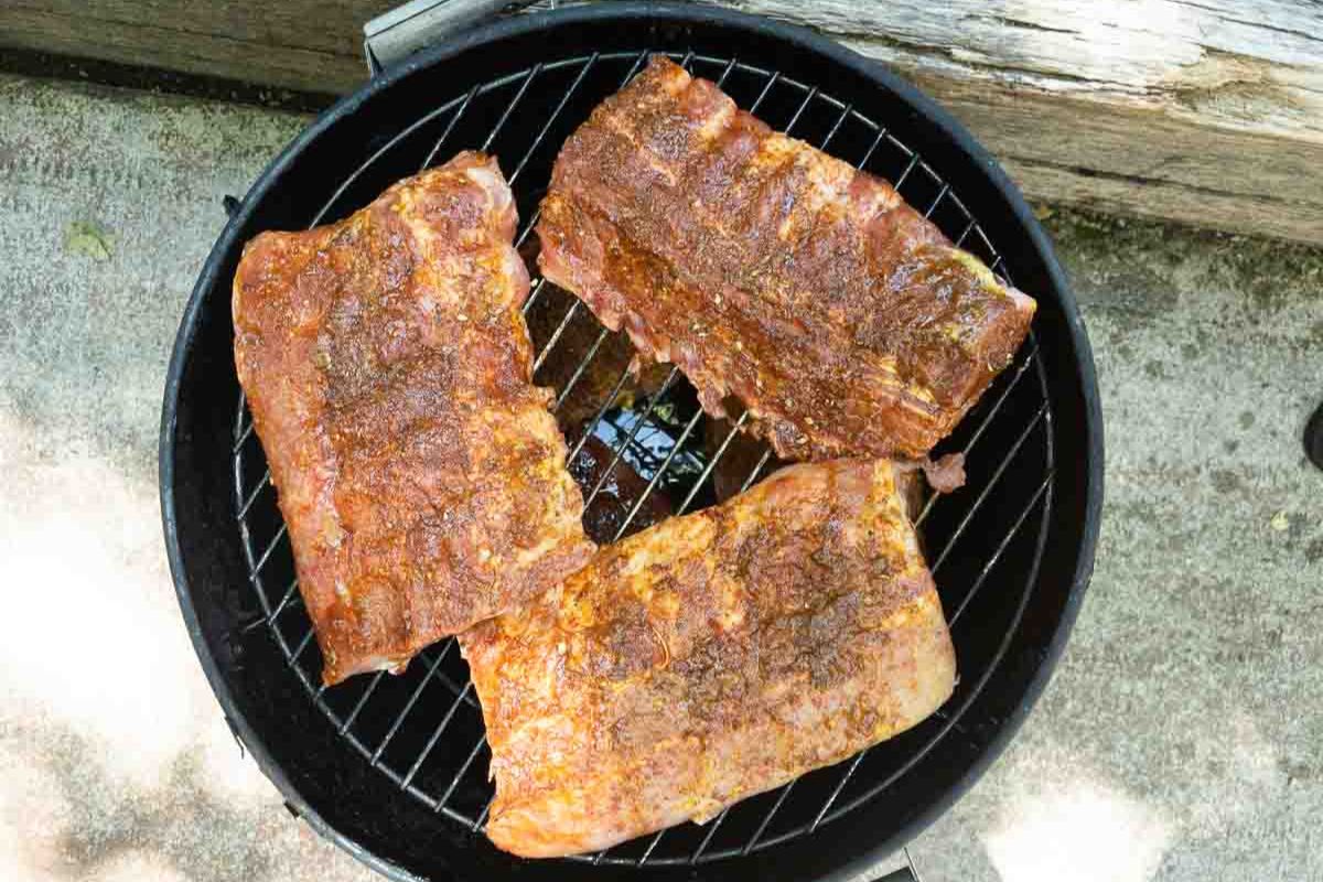 Seasoned baby back ribs on a smoker.