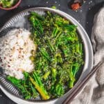 Stir fried broccolini with rice garnish with sesame seeds and some chili flakes served on a table.