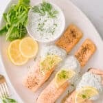 Close-up shot of Salmon yogurt with dill sauce garnished with lemon slices.
