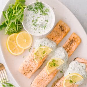 Close-up shot of Salmon yogurt with dill sauce garnished with lemon slices.