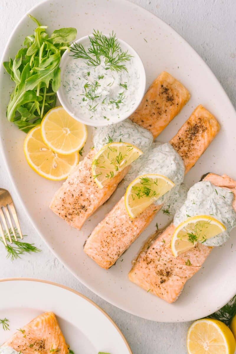 Baked salmon yogurt garnished with dill sauce and lemon slices.
