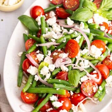 Close-up shot of Feta green bean salad on a white platter.