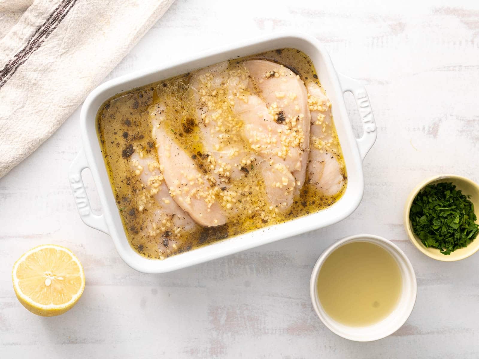 Marinated chicken breast meat in a baking dish resting on the countertop.