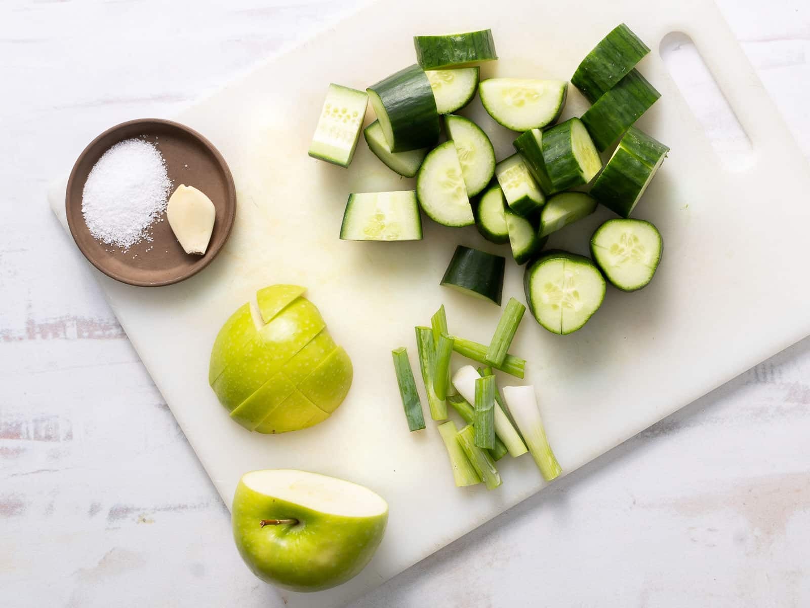 Cold cucumber soup ingredients placed on top of the vegetable cutting board.