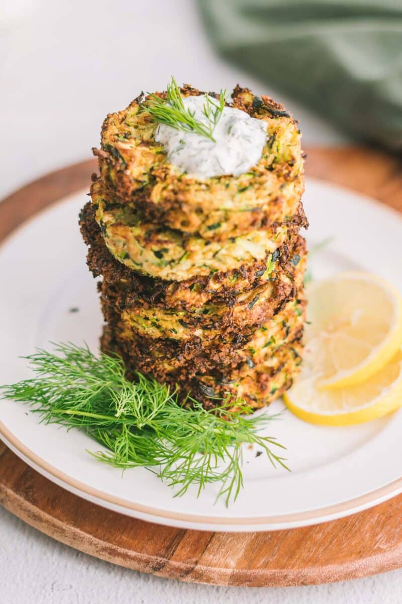 Stack of Zucchini fritters placed on the dinner plate atop the cutting board.