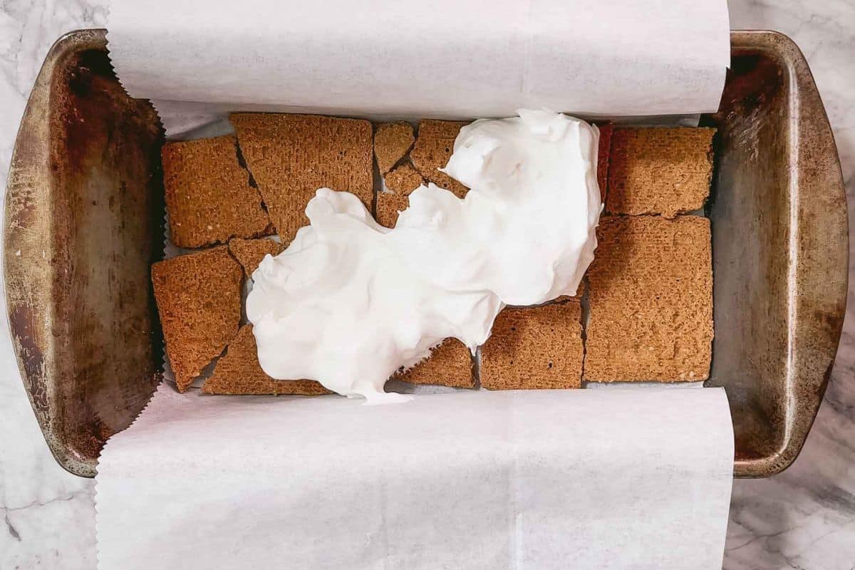 Layering crackers and cream fillings in a baking dish.