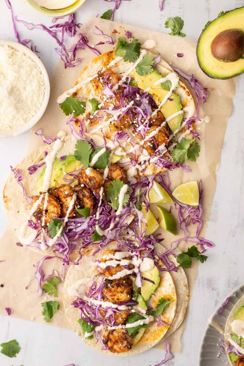 grilled shrimp tacos drizzled with Baja sauce resting on the table.