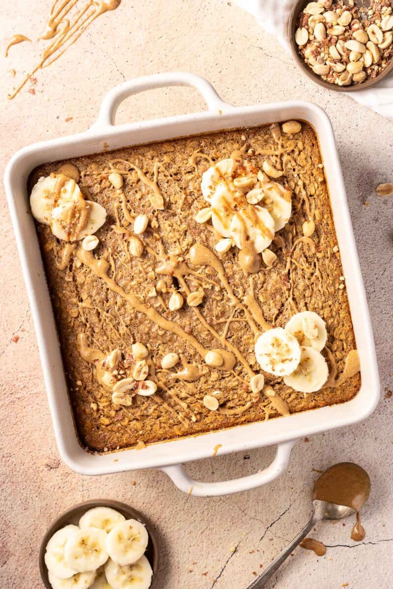 Baked Oatmeal Peanut Butter topped with slices of banana and nuts drizzled with peanut sauce.