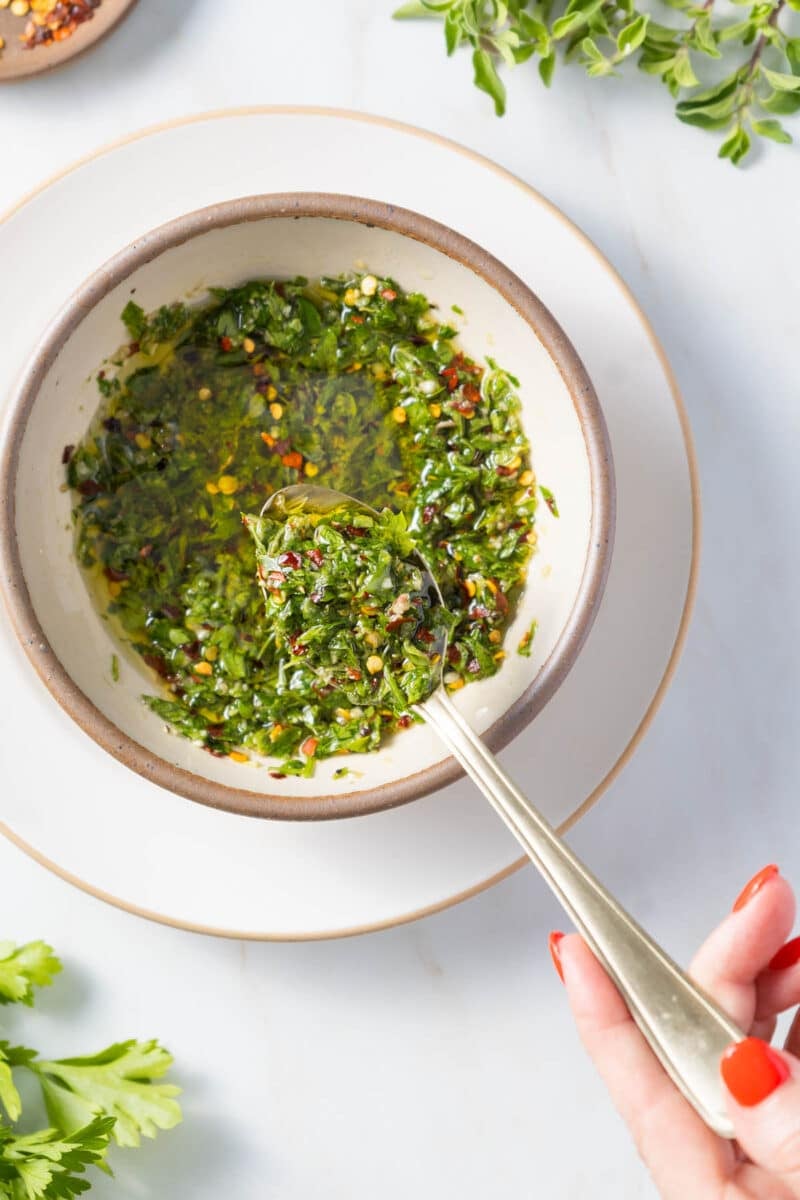 Authentic chimichurri sauce in a bowl with a spoon.