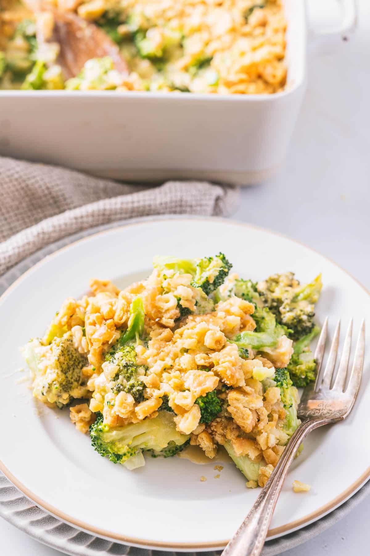 A portion of Gluten-free Broccoli Cheese casserole is being served on a dinner plate.