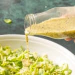 pouring poppyseed dressing on a salad.