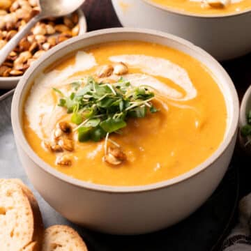 squash soup in a bowl with micro greens and toasted seeds.