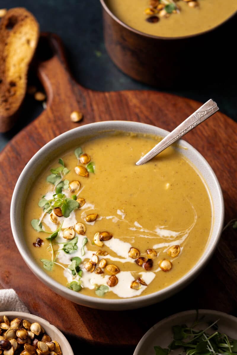 Delicata squash soup in a bowl with a pan in the background.