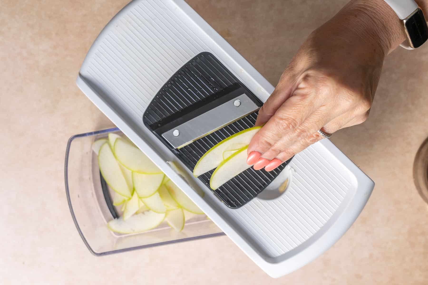 Thinly slicing the apples using a mandolin.
