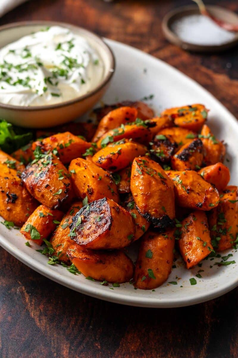 Roasted carrots on a serving platter with fresh herbs.