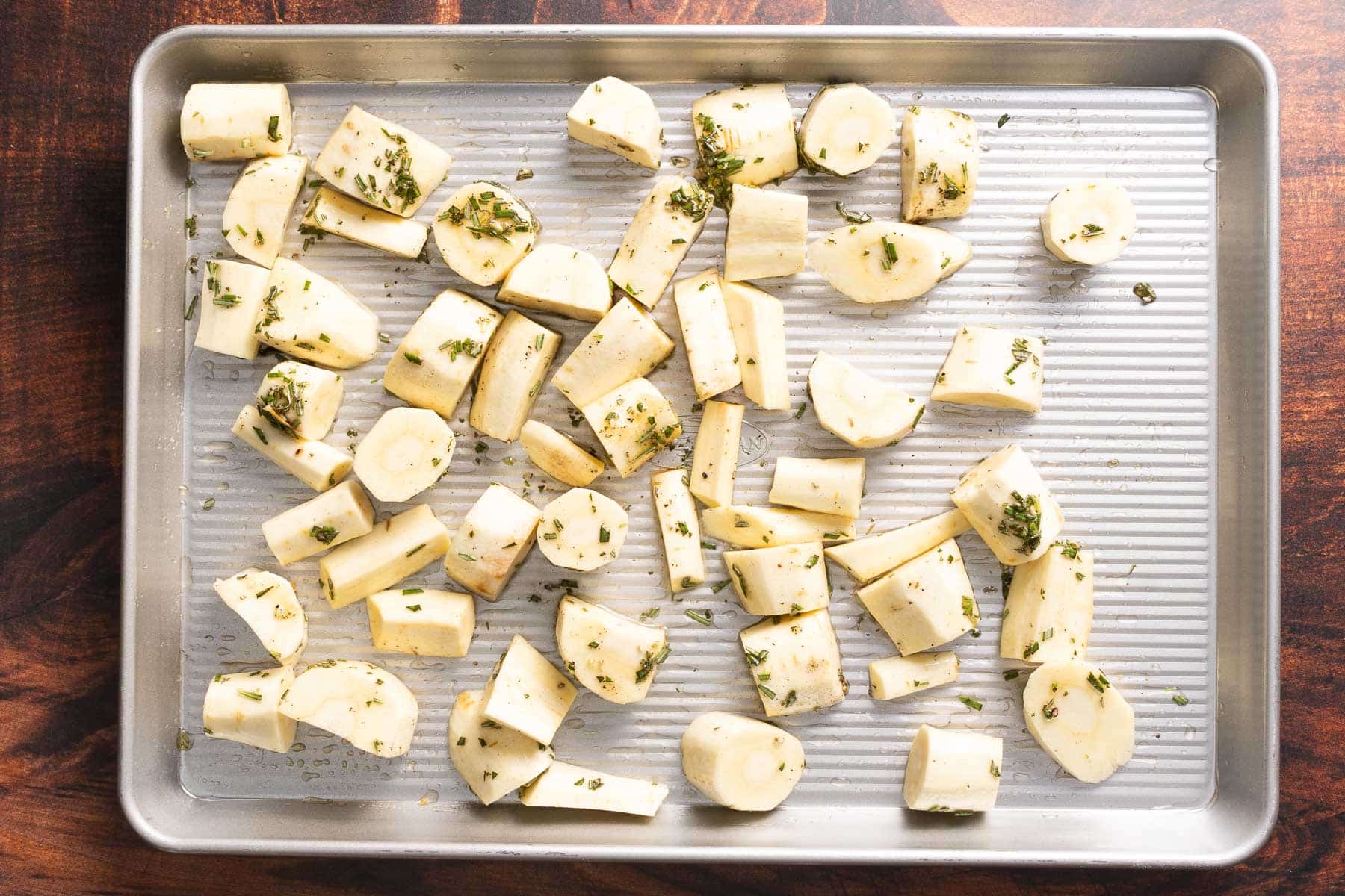 Raw parsnips in oil and honey before roasting.