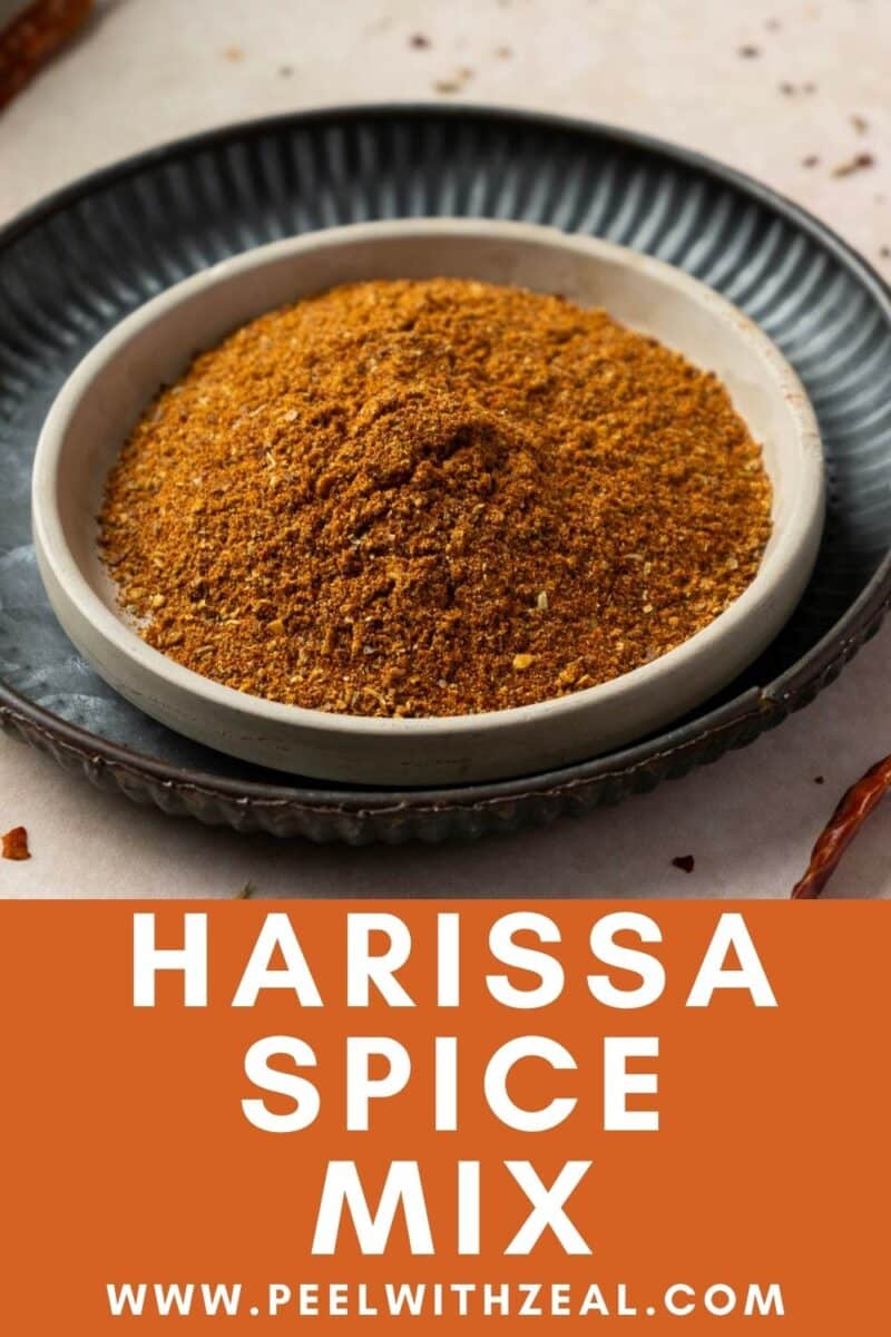 A bowl filled with harissa seasoning mix, placed on a black plate. Below the bowl, text reads "Harissa Spice Mix" and "www.peelwithzeal.com".