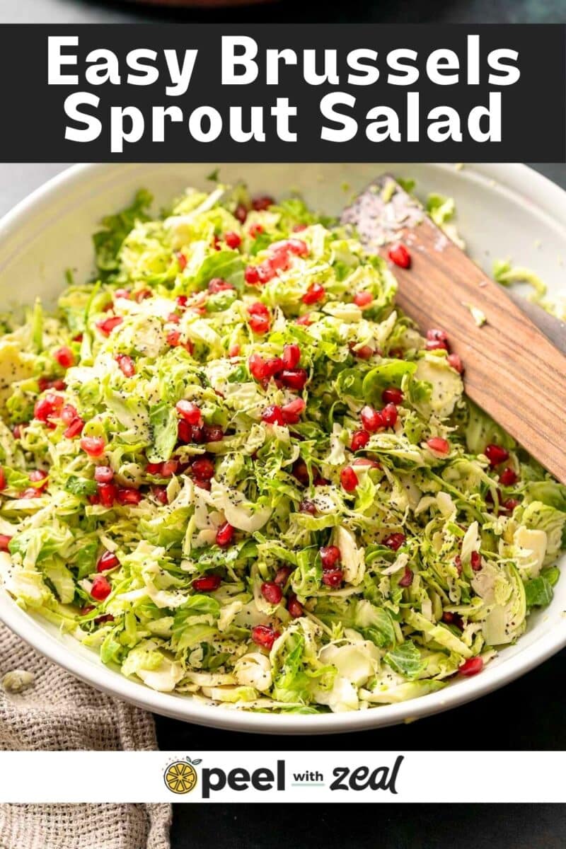 shaved brussels sprout salad with pomegranate in a white serving bowl.
